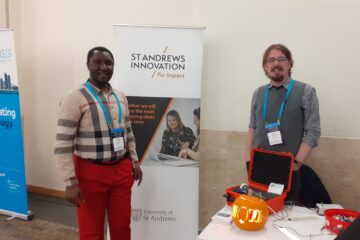 Edward (left) and Ross (right) presenting their work with lightwater sensors. In front of Ross is a table on which sits the OLED pumpkin and a red box containing some equipment