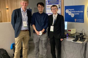 From left to right. Graham, Kou and Liam. on the right is some scientific equipment and behind them is a conference poster