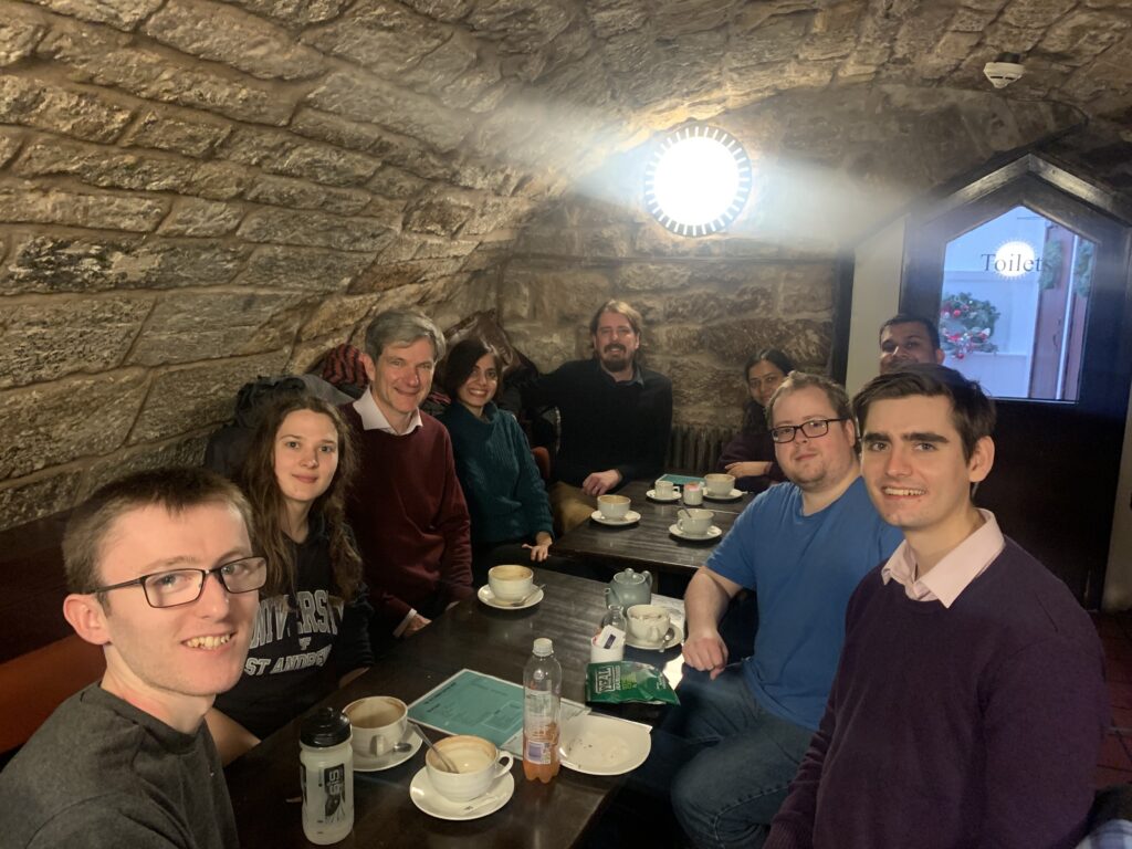 Some of the group are sat together under the stone walls and roof of the old students union. From front to back. Left: Liam, Egle, Ifor, Mina and Ross. Right: Thomas, David, Ramakant and Sagarika. 